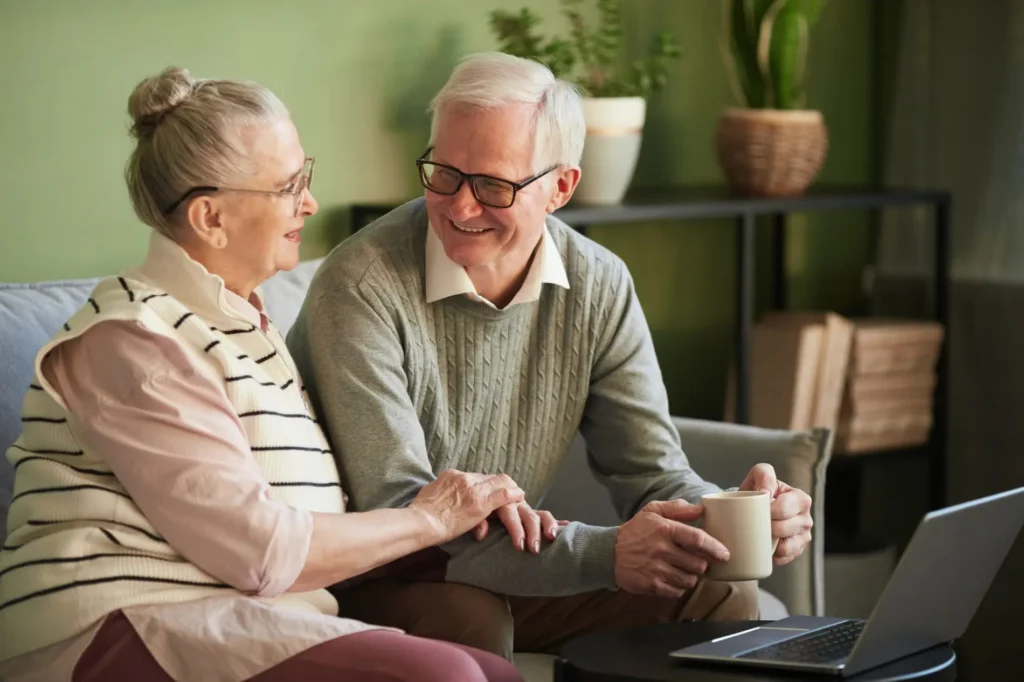 Happy senior husband and wife having talk while sitting on couch